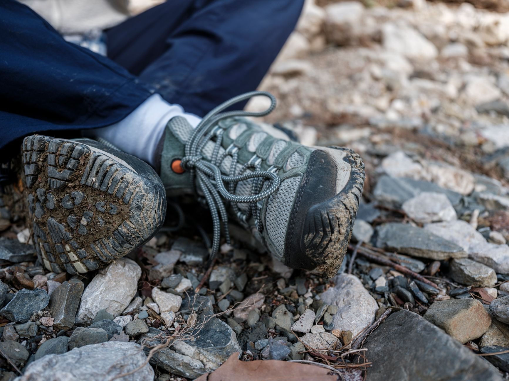 Botas de montaña con barro sobre un sendero rocoso